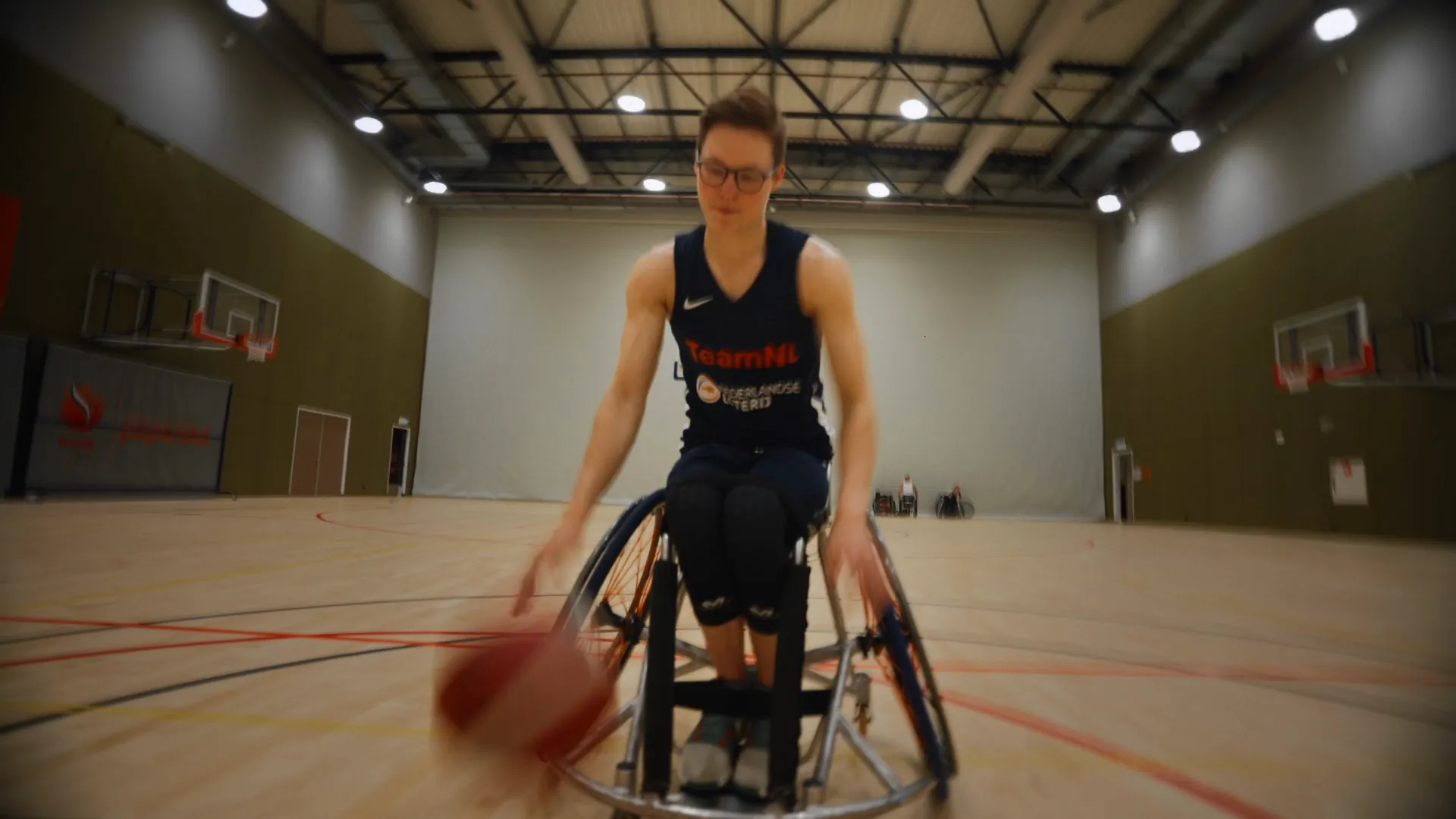 Rolstoelbasketbalster Bo Kramer dribbelt in de sporthal op Papendal